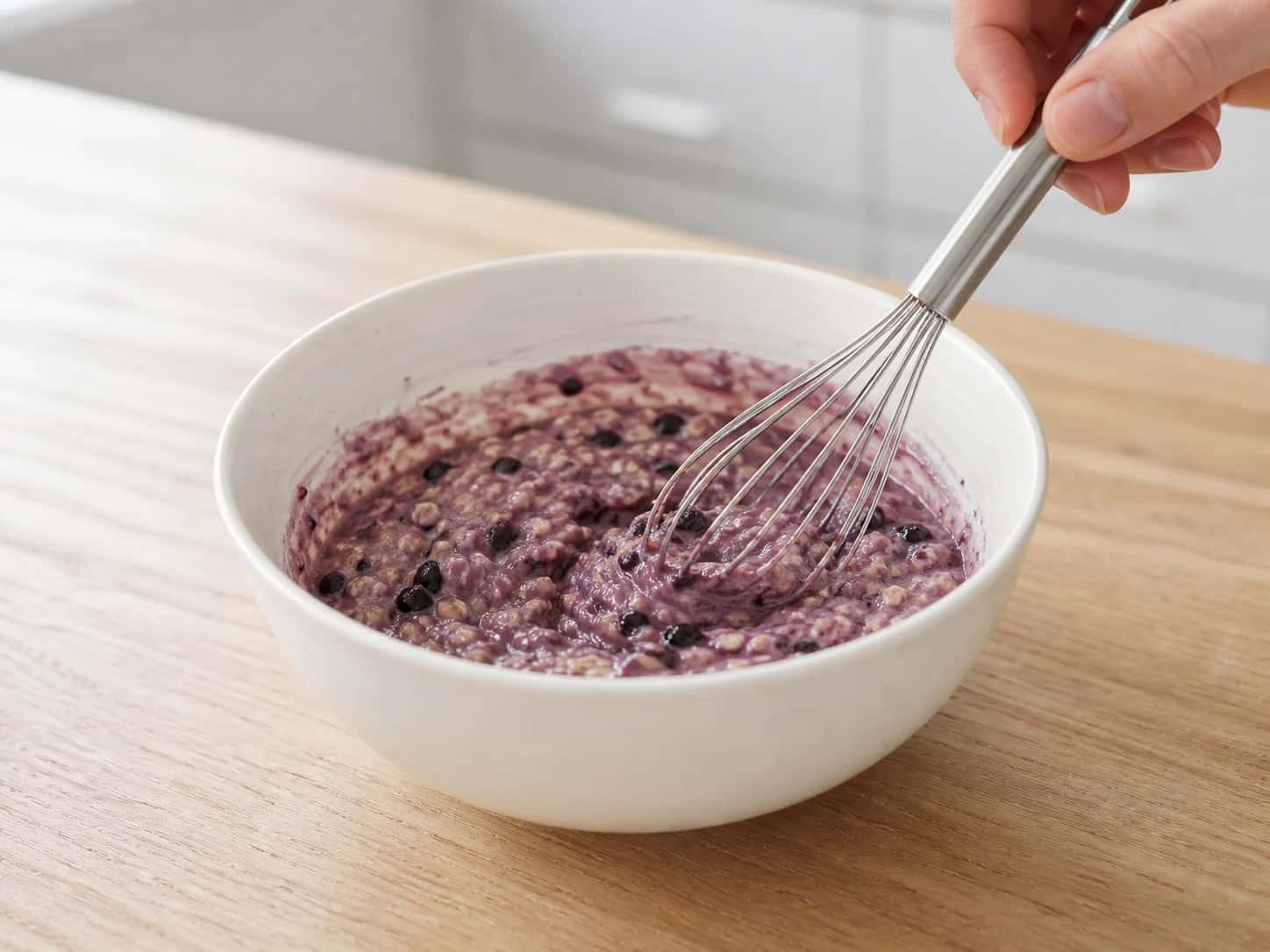 Step 2: Whisk the oat flour, beaten egg, mashed banana, half the water, and the remaining crushed blueberries into a thick spoonable batter. Let it rest for 3 minutes so the oat flour hydrates.
